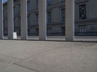 a person riding a skateboard next to some buildings on a concrete sidewalk in the middle of town