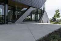 a person riding a skateboard on a cement sidewalk near a building with glass doors