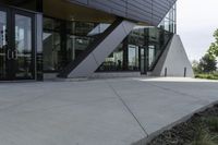 a person riding a skateboard on a cement sidewalk near a building with glass doors