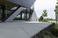 a person riding a skateboard on a cement sidewalk near a building with glass doors