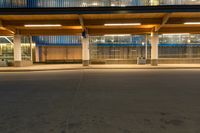 a person on a skateboard in front of an empty building at night with the light shining brightly