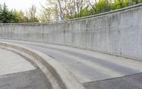 a skateboarder riding on a long, curved surface next to a concrete wall