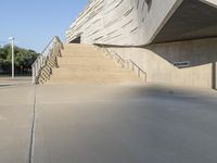 a skateboarder doing tricks in an empty building near steps to another building with concrete walls