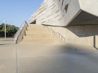 a skateboarder doing tricks in an empty building near steps to another building with concrete walls