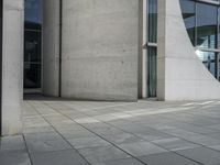 a person skateboarding and doing a trick on the sidewalk outside a building with large windows