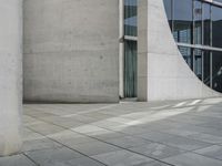 a person skateboarding and doing a trick on the sidewalk outside a building with large windows