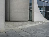 a person skateboarding and doing a trick on the sidewalk outside a building with large windows