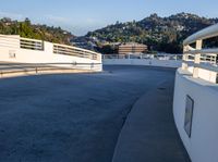 the skate boarder is doing tricks near the edge of the bridge over looking a hilly landscape