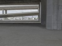 a man is on a skateboard under a bridge between two large concrete pillars and another white one