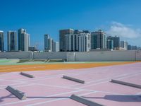 a man rides his skateboard on an orange and pink track with a cityscape background