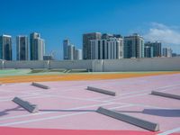 a man rides his skateboard on an orange and pink track with a cityscape background