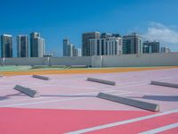 a man rides his skateboard on an orange and pink track with a cityscape background