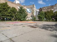 a skateboarder is standing on his board in a big empty parking lot with graffiti all over the road