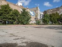 a skateboarder is standing on his board in a big empty parking lot with graffiti all over the road