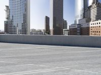 a skateboarder on an empty cement surface in the city below tall buildings and a ramp