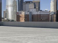 a skateboarder on an empty cement surface in the city below tall buildings and a ramp