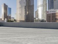 a skateboarder on an empty cement surface in the city below tall buildings and a ramp