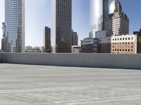 a skateboarder on an empty cement surface in the city below tall buildings and a ramp