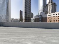 a skateboarder on an empty cement surface in the city below tall buildings and a ramp