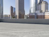 a skateboarder on an empty cement surface in the city below tall buildings and a ramp