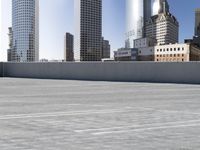 a skateboarder on an empty cement surface in the city below tall buildings and a ramp