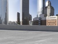 a skateboarder on an empty cement surface in the city below tall buildings and a ramp