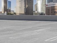 a skateboarder on an empty cement surface in the city below tall buildings and a ramp