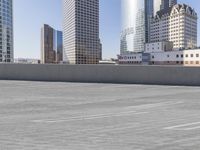 a skateboarder on an empty cement surface in the city below tall buildings and a ramp