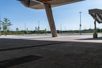 a man skate boarding in a public open area with blue skies above him and tall buildings to the right