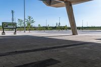 a man skate boarding in a public open area with blue skies above him and tall buildings to the right