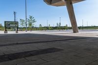 a man skate boarding in a public open area with blue skies above him and tall buildings to the right