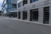 the skateboarder rides down the empty streets near tall buildings on an overcast day