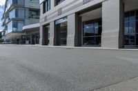 the skateboarder rides down the empty streets near tall buildings on an overcast day