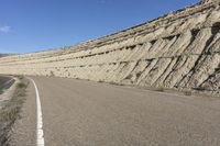 the man is riding his skateboard along a deserted road near the mountains in a windy day