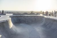 a man riding his skateboard through the middle of a concrete bowl at a skate park