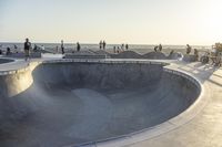 a man riding his skateboard through the middle of a concrete bowl at a skate park