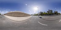 a skateboarder doing a trick at the skatepark near an empty road with buildings and palm trees