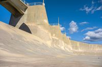 a boy skates through the middle of a large concrete ramp, under a blue sky