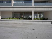 a man is skating in an open courtyard next to tall buildings on a sunny day