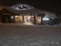 a ski lodge at night with people inside during wintertime and snow drift around them