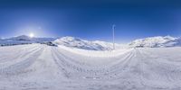 a view of some ski slopes with a person skiing down one hill of them and a mountain range on the other side