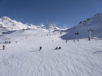 a ski slope full of people with skiers up to the top of it and hills in the background