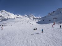 a ski slope full of people with skiers up to the top of it and hills in the background