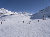 a ski slope full of people with skiers up to the top of it and hills in the background