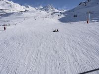 a ski slope full of people with skiers up to the top of it and hills in the background