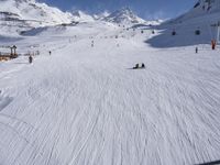 a ski slope full of people with skiers up to the top of it and hills in the background