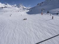 a ski slope full of people with skiers up to the top of it and hills in the background