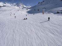 a ski slope full of people with skiers up to the top of it and hills in the background