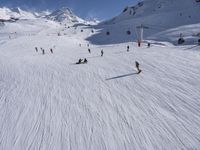 a ski slope full of people with skiers up to the top of it and hills in the background