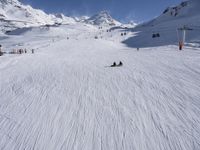 a ski slope full of people with skiers up to the top of it and hills in the background